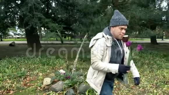 无家可归的男人在公园的花坛上为他的女人摘花视频的预览图