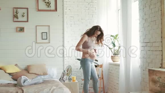 肚皮妈妈在卧室里看肚子站在窗边的孕妇视频的预览图