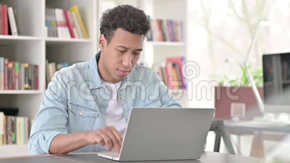 年轻的非裔美国人颈部疼痛在做手提电脑视频的预览图