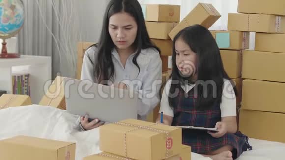 亚洲姐妹使用平板电脑检查要交付给客户的产品视频的预览图