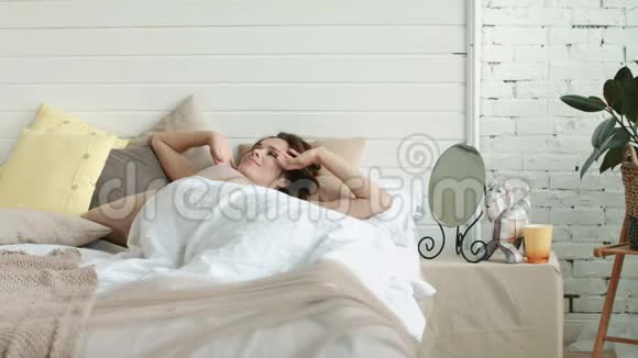 微笑的女人伸展身体晨间卧室漂亮的女孩躺在家里的床上视频的预览图