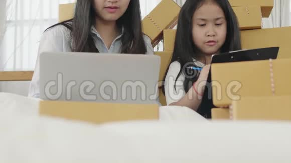 亚洲姐妹使用平板电脑检查要交付给客户的产品视频的预览图