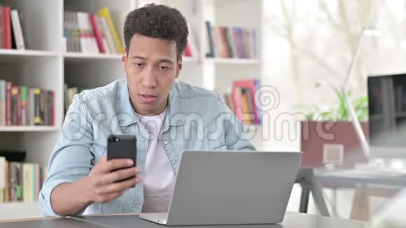 年轻的非裔美国人工作智能手机和笔记本电脑视频的预览图