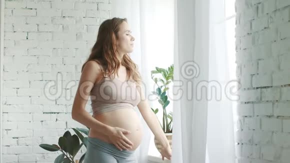 孕妇站在房间里期待妈妈在家看窗户视频的预览图