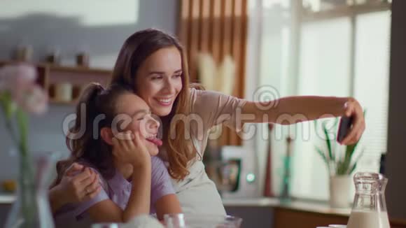 母女俩在厨房的智能手机上自拍视频的预览图