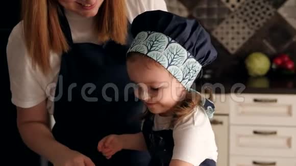 母亲和女儿在厨房里玩得很开心女孩用面粉涂抹母亲的脸视频的预览图