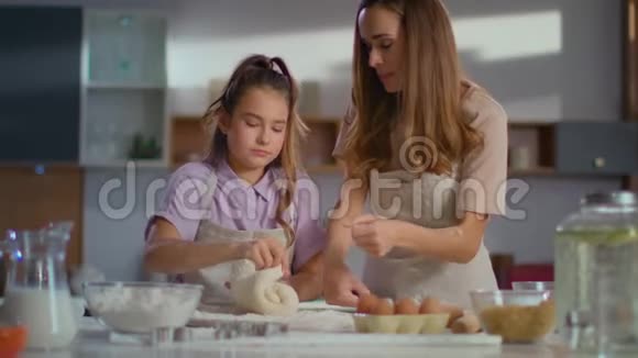 妈妈教女儿慢动作地在厨房里捏面团做饼干视频的预览图