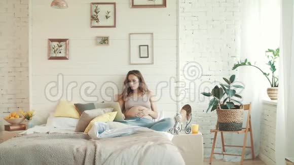 快乐的孕妇在家里使用笔记本电脑准妈妈坐卧室视频的预览图