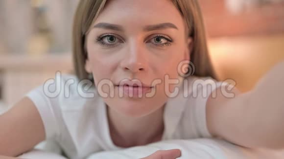 在床上做视频聊天的开朗的年轻女性视频的预览图