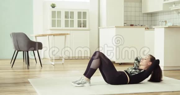 年轻女子正在家里的地板上做腹部运动侧视视频的预览图