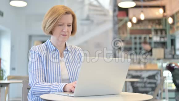 创意老女人在咖啡厅用笔记本电脑倒掉大拇指视频的预览图