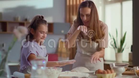 母亲和女儿慢吞吞地拍着厨房里的面粉视频的预览图