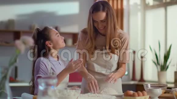 女孩在厨房里用面粉涂抹母亲的鼻子家庭在家的时间视频的预览图