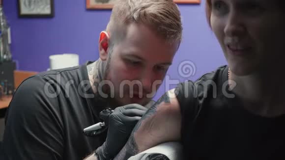 青年纹身师在沙龙中纹身蛇的录像过程视频的预览图