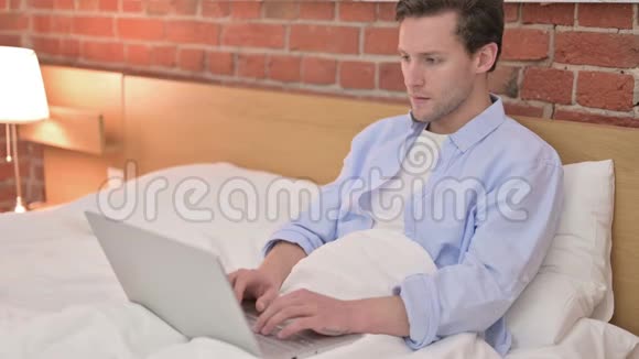年轻人在床上的笔记本电脑上尿尿视频的预览图