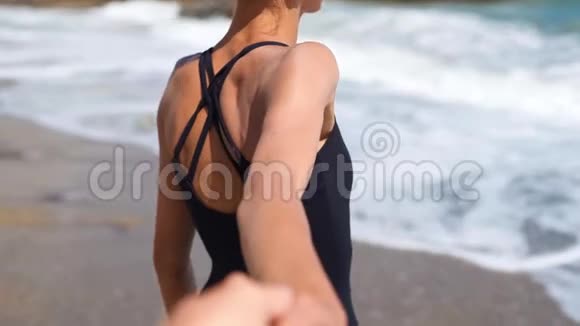 年轻夫妇牵着手女孩牵着男朋友走在美丽的阳光下波浪般的沙滩上视频的预览图