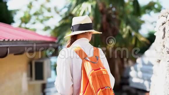 泰国度假期间戴着草帽白衬衫和橙色背包的免费女游客微笑着独自享受视频的预览图