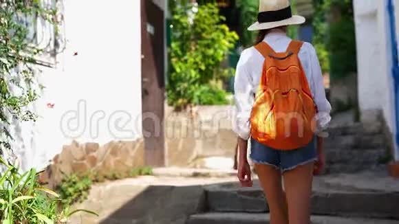 镜头跟随迷人的性感女人穿着牛仔裤短裤的长腿穿着草帽白色衬衫和橙色的女孩视频的预览图