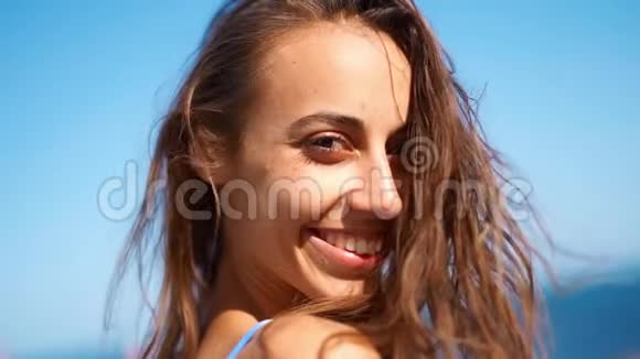 特写慢动作美丽的晒黑女人走在海滩上回头看镜头微笑视频的预览图