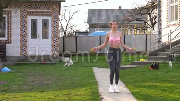 家里有跳绳的健康年轻女子的画像女健身者在阳光明媚的日子在户外做跳绳运动视频的预览图