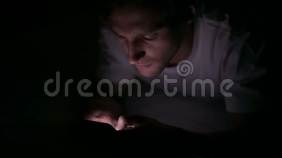晚上在床上用智能手机专注的年轻人视频的预览图