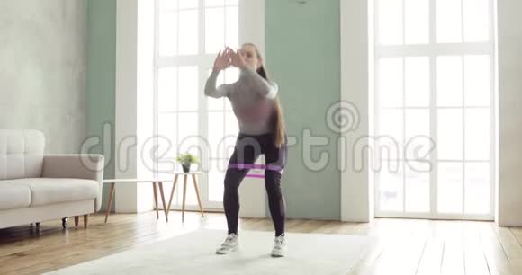 运动型女性在家里的起居室里练习下蹲和弓箭步视频的预览图