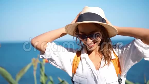 阳光明媚的海边慢镜头特写迷人的快乐女孩旅游草帽和眼镜视频的预览图