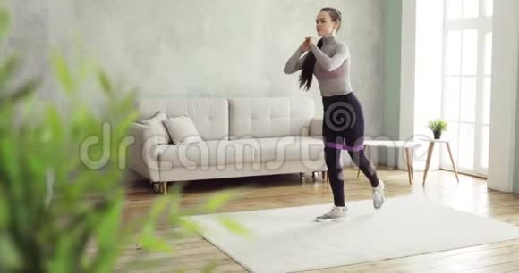 女人正在训练做蹲和在家里在客厅侧视视频的预览图