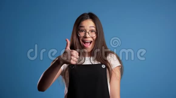 年轻的亚洲女人完美的化妆在蓝色背景上竖起大拇指赢家视频的预览图