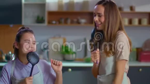 母女俩在厨房里用勺子唱歌家庭在家玩得开心视频的预览图