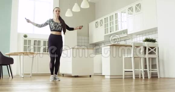 年轻的运动女子正在厨房里跳绳做有氧训练视频的预览图