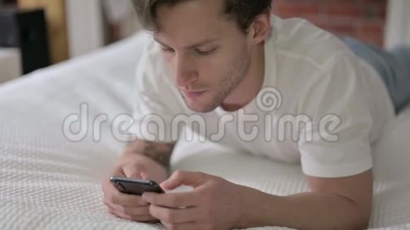 年轻人在床上使用智能手机感到震惊视频的预览图