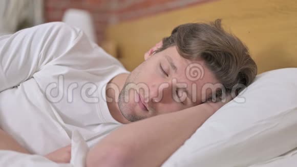 英俊的年轻人在床上小睡的画像视频的预览图