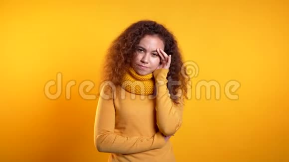 年轻漂亮的心烦意乱的女人卷发在黄色的工作室肖像上女孩把手放在头上问题的概念视频的预览图