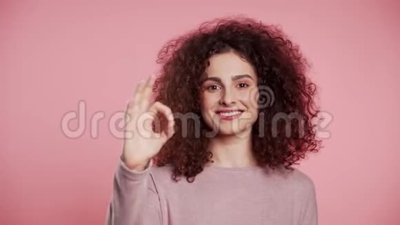 赢家成功积极的女孩在粉红色背景上做OK标志微笑视频的预览图