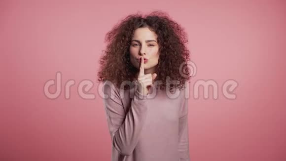 积极的女孩用手指在她的嘴唇上的粉红色背景什赫的姿态视频的预览图