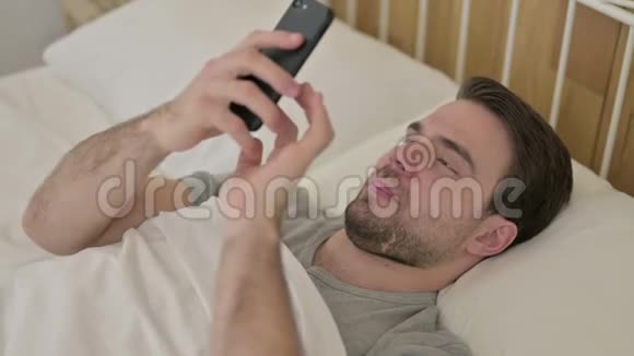 在床上使用智能手机进行视频聊天的少年视频的预览图