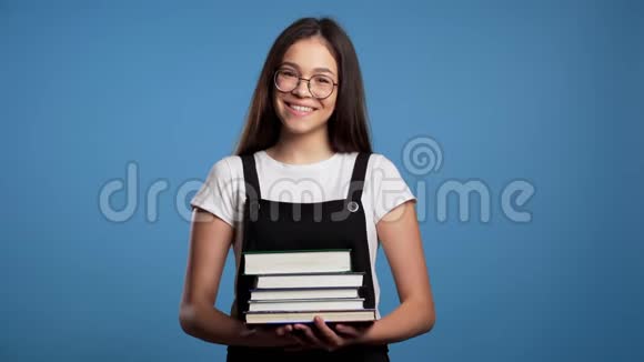 工作室里蓝底的亚洲学生女孩从图书馆拿着一叠大学书籍视频的预览图
