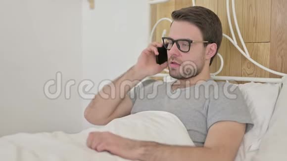 在床上用智能手机说话的大学生视频的预览图
