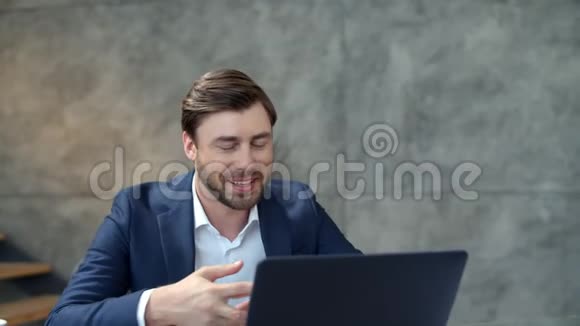 微笑的商人在办公室的笔记本电脑相机上在线聊天一个挥舞着手的人视频的预览图