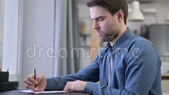 大胡子青年在办公室写文件视频的预览图