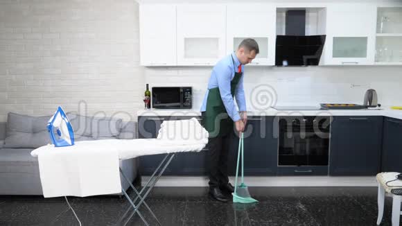 穿着领带和围裙的帅哥在厨房扫地视频的预览图
