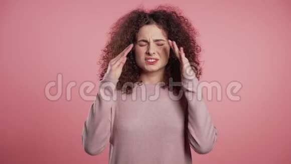 一位留着卷发头痛的年轻美女粉色画室肖像视频的预览图
