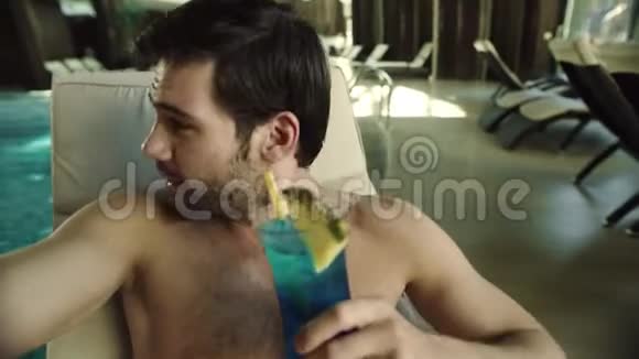 酒店的人在泳池边喝鸡尾酒快乐男子录制视频视频的预览图