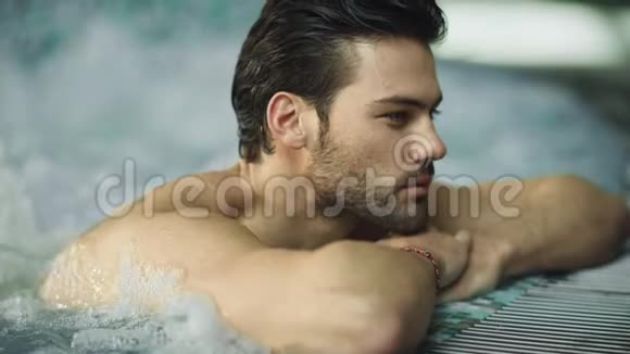 性感男人享受按摩浴缸的肖像帅哥在游泳池里放松视频的预览图