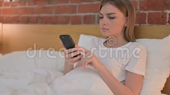在床上使用智能手机让年轻女性愤怒视频的预览图