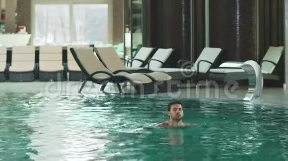 微笑的人在现代酒店游泳性感的家伙在室内豪华游泳池洗澡视频的预览图