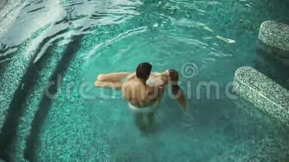 顶景夫妇享受温泉酒店的游泳池一对在水疗中心休息的情侣视频的预览图