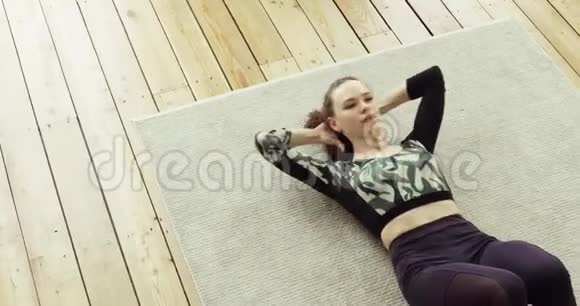 运动的年轻女子正在家里的地板上做腹肌练习俯视图视频的预览图