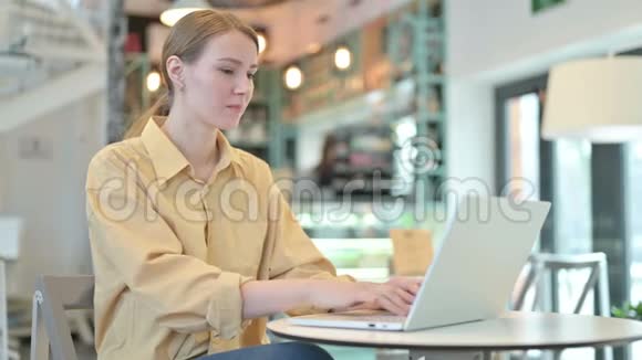 背疼的年轻女子在咖啡厅用笔记本电脑视频的预览图